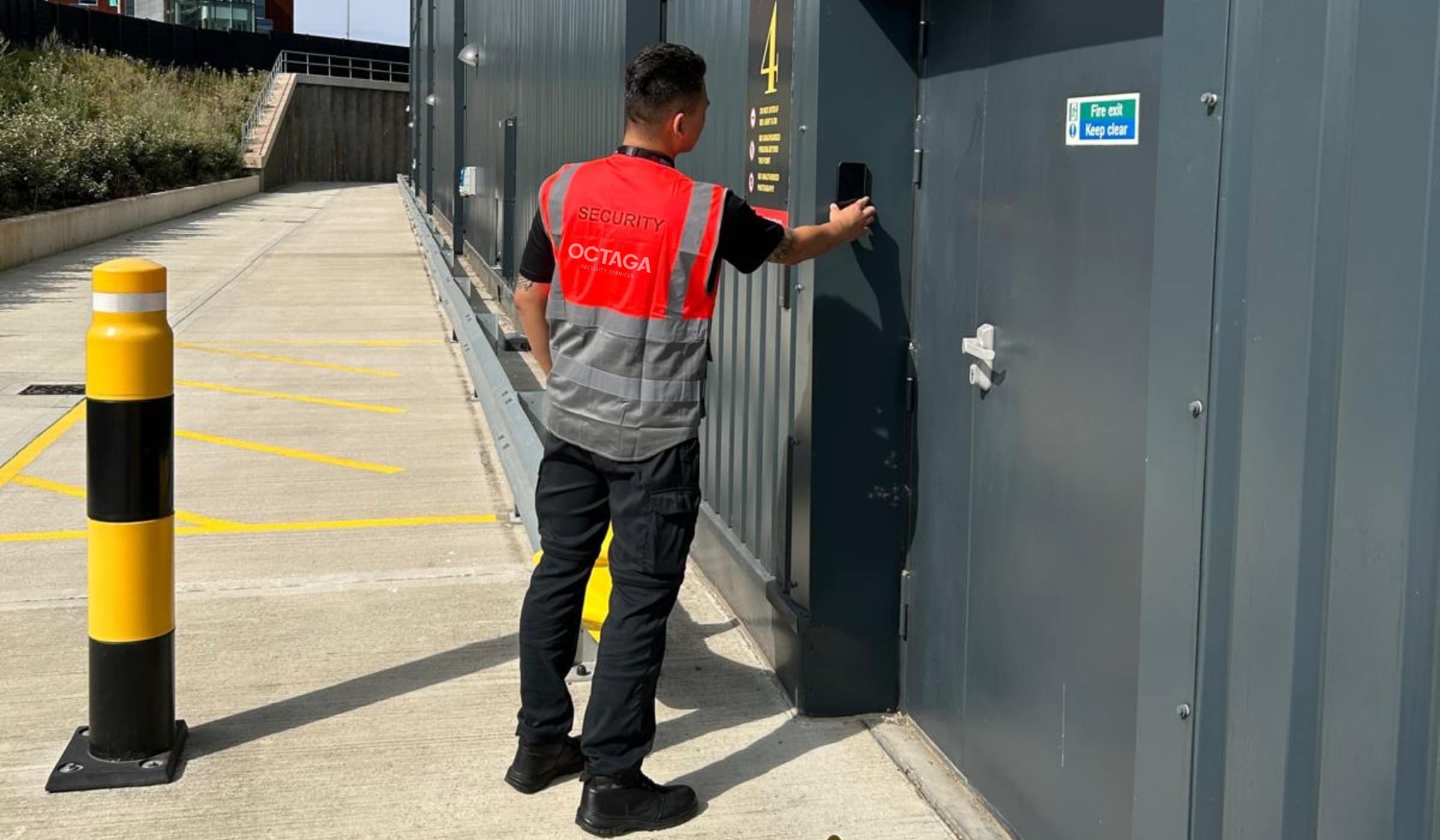 Octaga security officer in hi-vis vest using a mobile device to access a secured site on an alarm response call-out