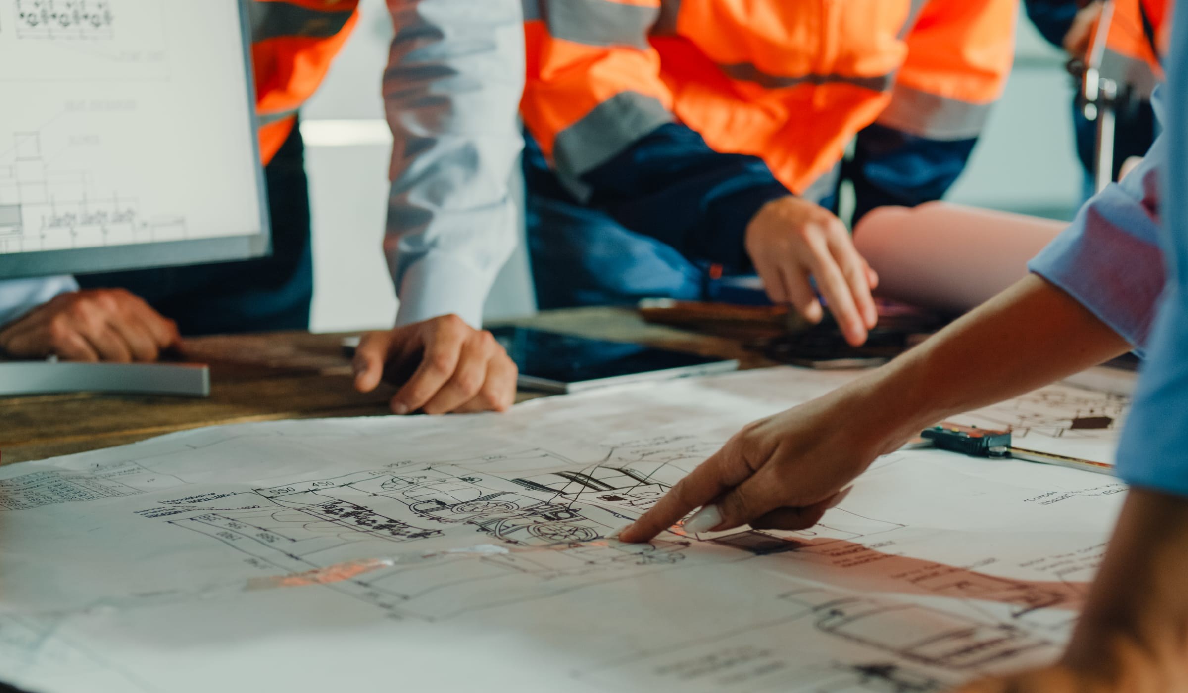 Risk consultancy team in hi-vis jackets planning protective security measures around site drawings