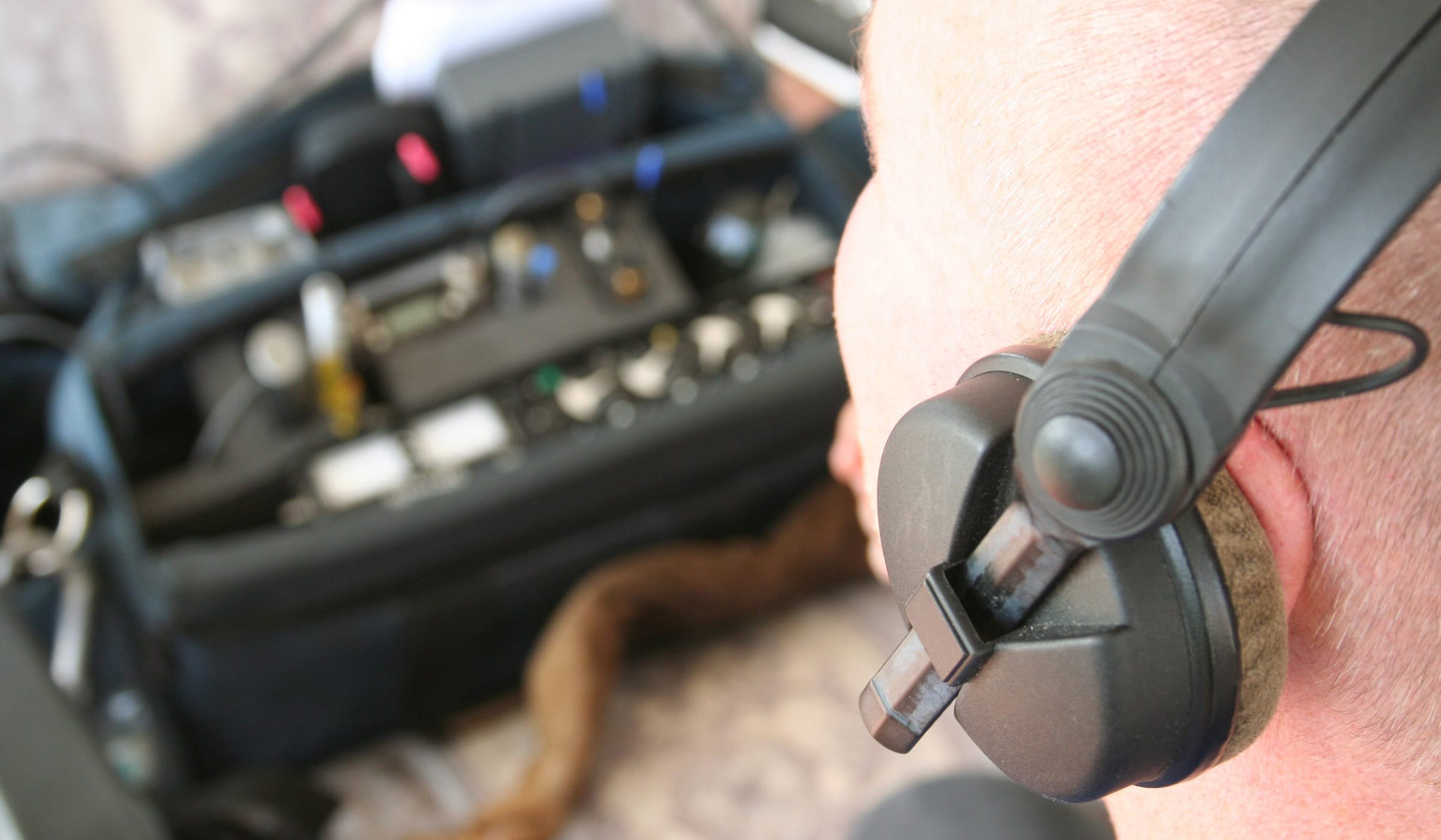 Technical surveillance countermeasures specialist wearing a headset beside radio equipment during a TSCM sweep
